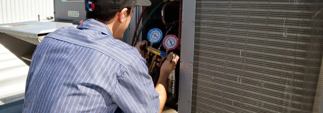 HVAC technician servicing a condenser unit in Avon